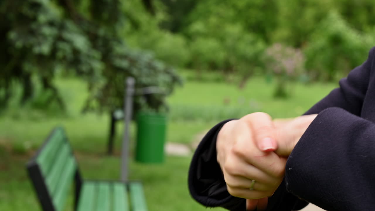Close up of hands pouring clear sanitizer gel from a small bottle in a park