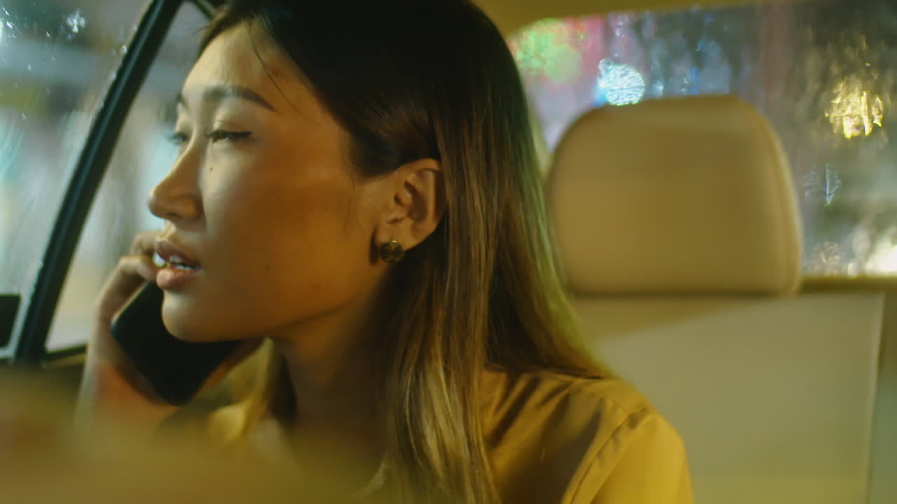 Asian Woman Speaking on Phone in Taxi at Night