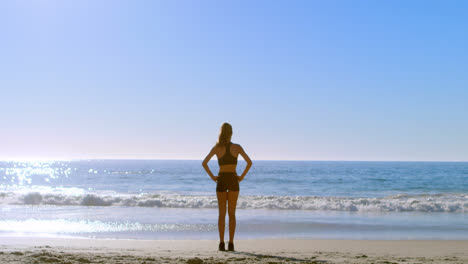 fit woman standing with hands on hip in the beach 4k