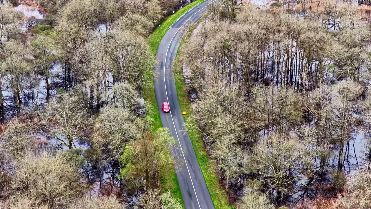 Luftfoto af en rød bil på en vej i den oversvømmede regionale naturpark Briere.