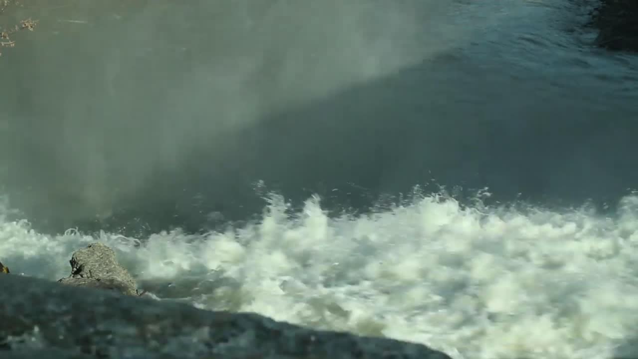 Stream running fast in summer green forest. Small waterfall with crystal clear water. Stones and logs covered with water. Steadicam shot in 4K,