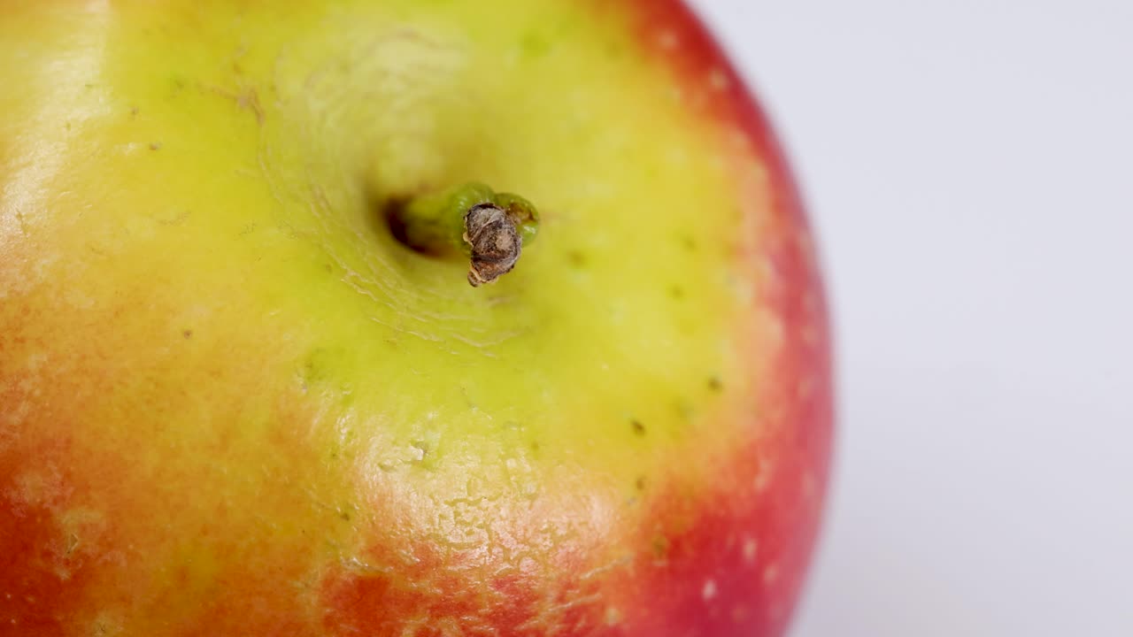 Macro video of a rotating apple with vibrant red and green hues, captured in bright, even lighting