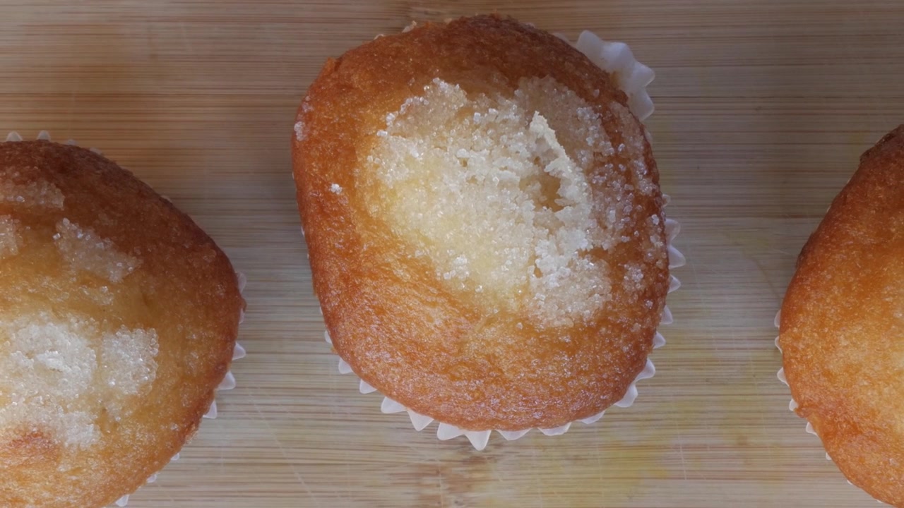 Primer plano de muffins recién horneados con azúcar por encima sobre una superficie de madera.