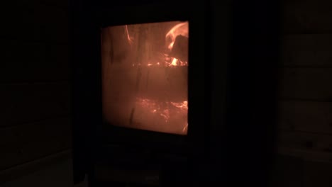 Static-shot-of-wood-burning-in-a-sauna-oven,-glass-door-closed,-closer-to-heat