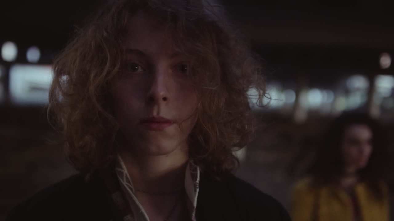 Two individuals under an urban underpass at night