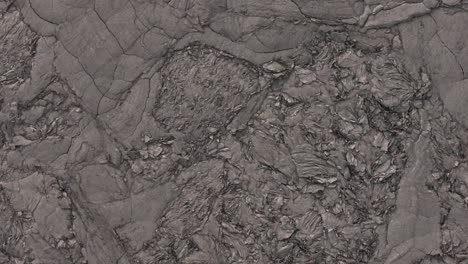 a top-down aerial view reveals the intricate textures of the icelandic ground, showcasing a diverse landscape of rugged volcanic rock, dark earth, and remnants of snow or ice