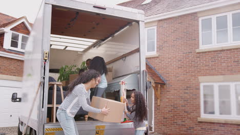 Familia-Descargando-Muebles-Del-Camión-De-Mudanzas-A-Una-Nueva-Casa.