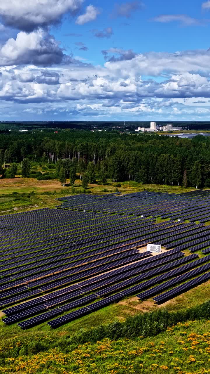 Wide view of solar panels in a field under a blue sky with clouds