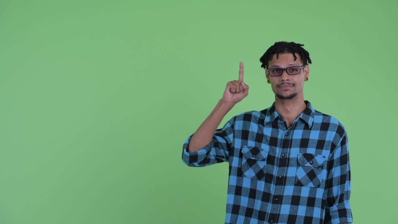 Giovane e bel uomo hipster africano felice che mostra qualcosa