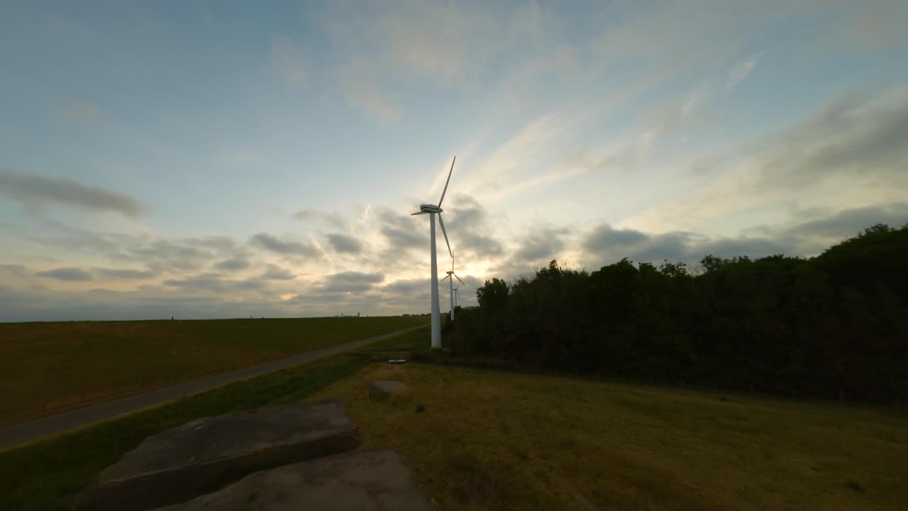 White windmills producing energy on the borderline between urban and rural environment