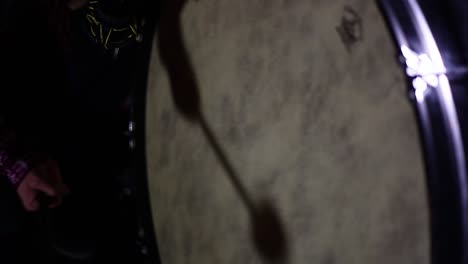 a man playing a large drum in a dark room, close up.