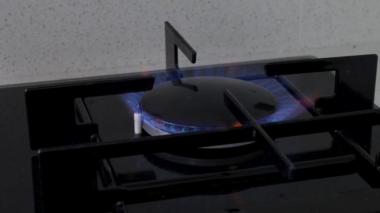 Close-up of a large kitchen gas stove burner with a blue flame, symbolizing cooking, heating, and meal preparation in a home kitchen