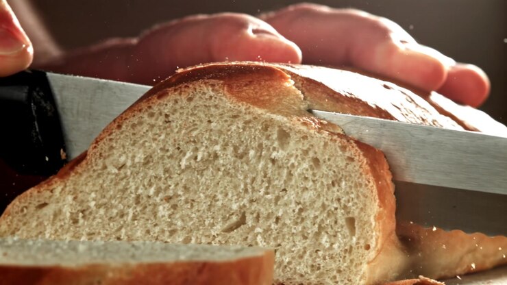Slicing Freshly Baked Bread with a Serrated Knife in Slow Motion