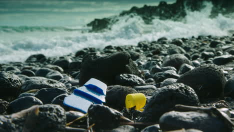 stunning low level shot of a wave washing over plastic rubbish on a pebbly beach