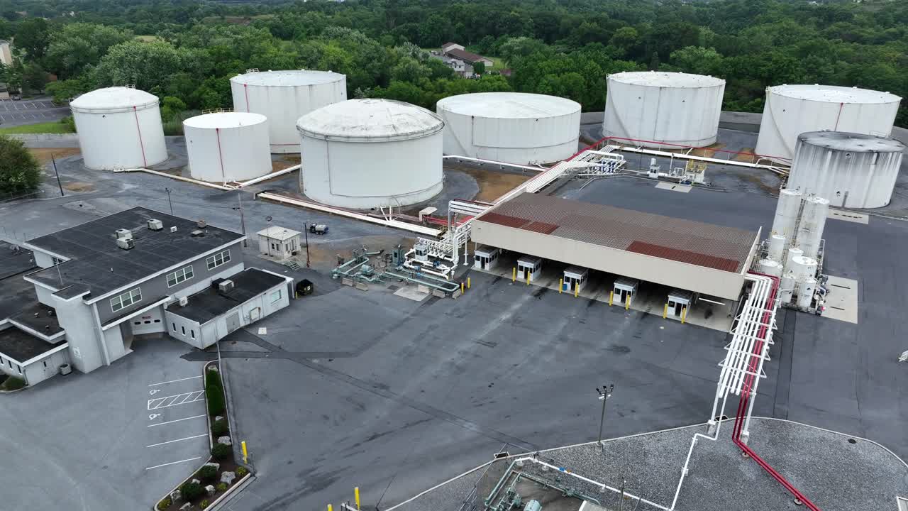 Industrial fuel terminal in American suburb town. Aerial approaching shot. Building and fuel silo tanks in town of Harrisburg, Pennsylvania. Wide shot