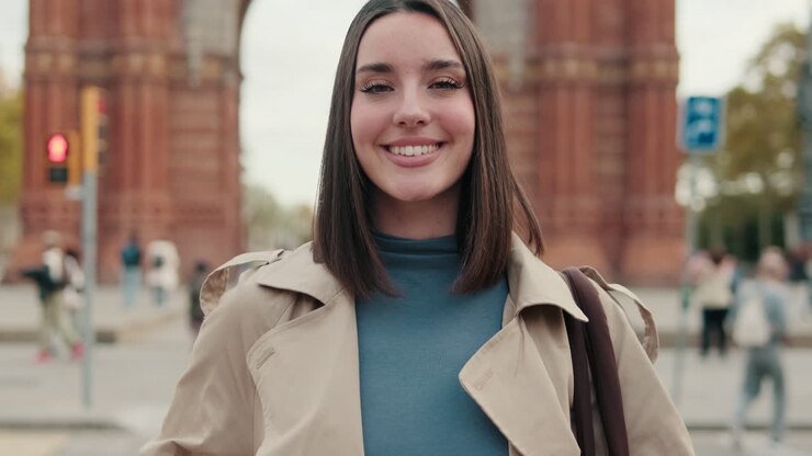 Smiling Young Woman in Trench Coat Standing in City Street