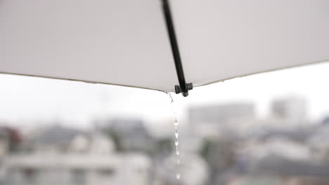 drops of water flow down from the surface of the white parasol during rainy season