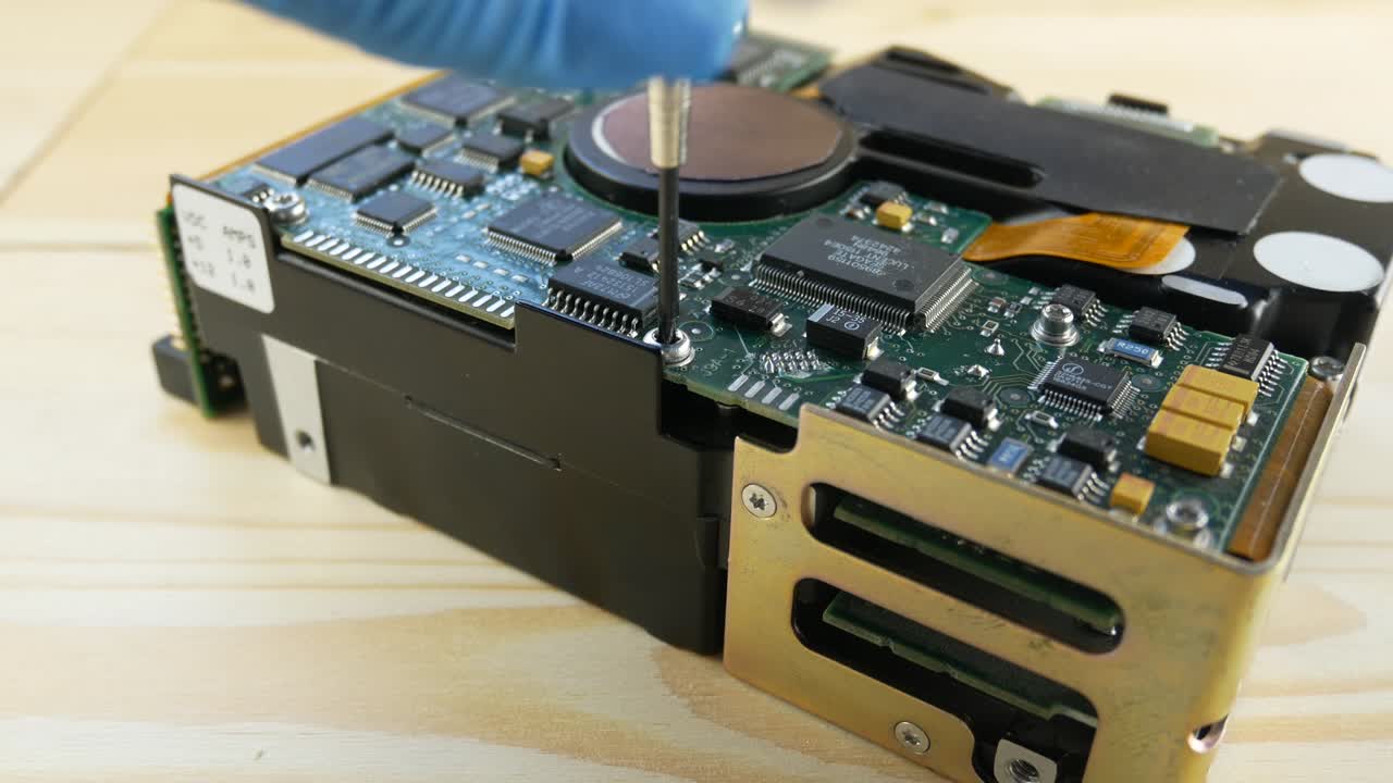 파란 장갑을 입은 손으로 하드 드라이브의 스크루를 단단히