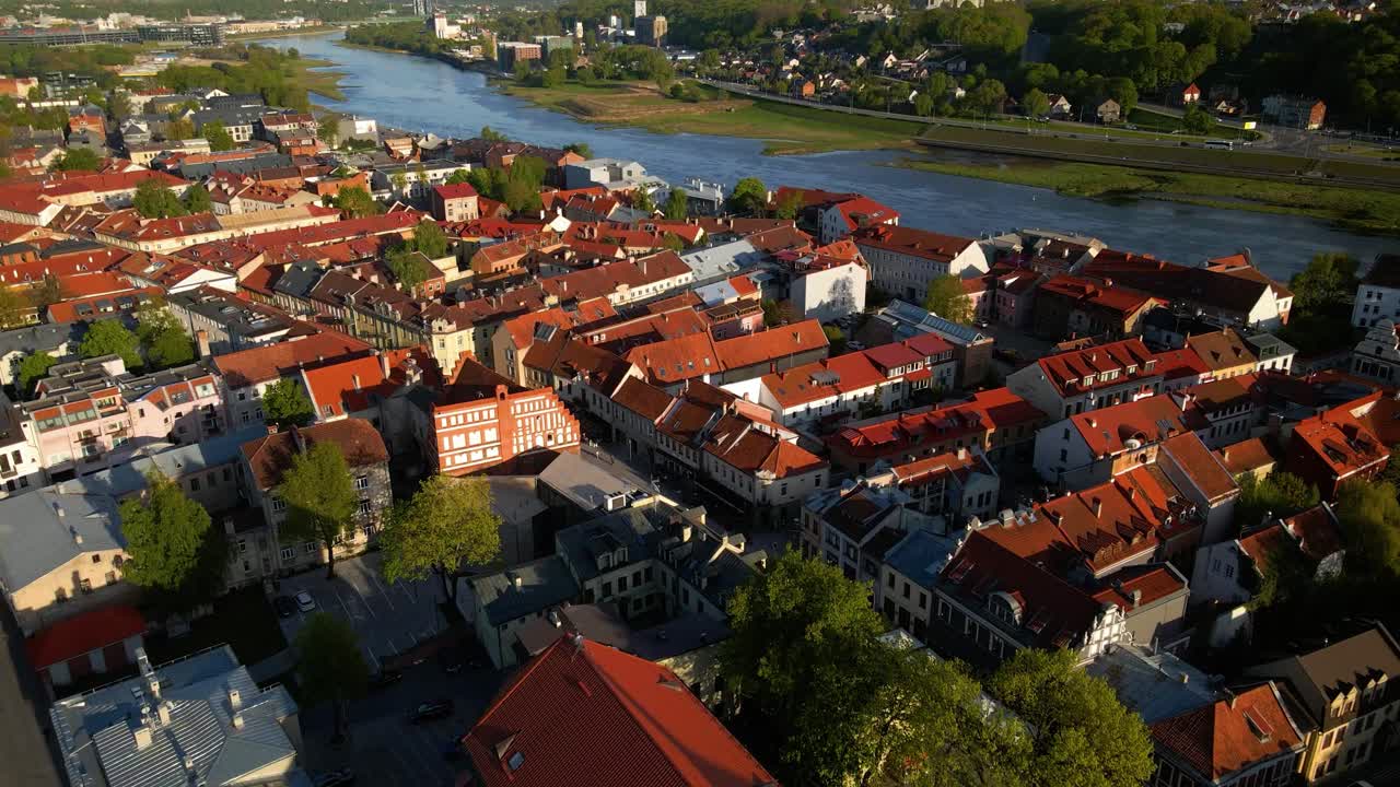fotografía aérea de casas históricas y calles estrechas en el casco antiguo de kaunas junto al río nemunas en lituania en una noche soleada, alejándose