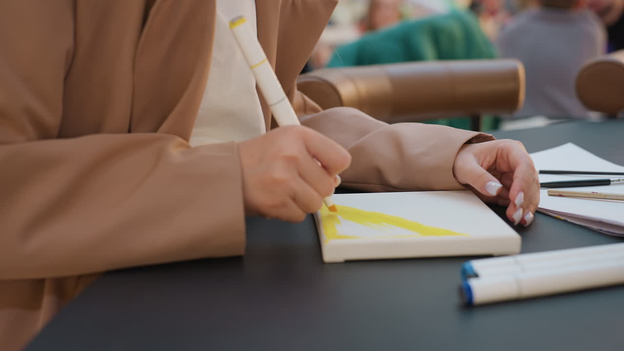 Mujer tomando notas en una cafetería, joven apuntando notas en un centro comercial, chica usando un bolígrafo para escribir en una cafetería concurrida, joven concentrada en sus notas mientras está sentada en la cafetería de un centro comercial