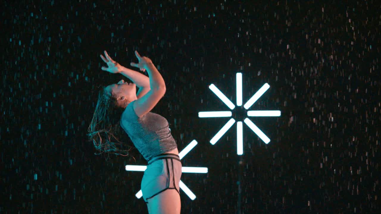 Caucasian woman seductive modern dancer wet in rain, slow motion effect