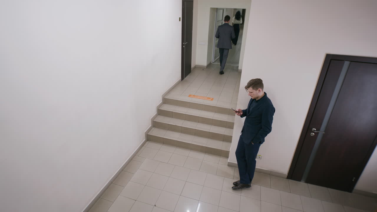 Men with smartphones in a modern office building hallway