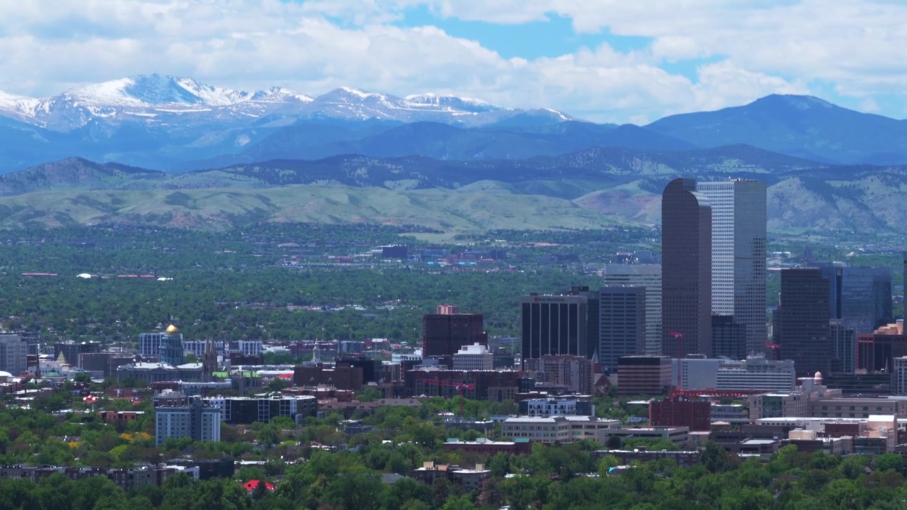 Drone-luftfoto af skyskraber-skyline i Front Range, Denver, Colorado (Mile High City), med Capitol-bygninger, en forårsmorgen under blå himmel, grønne områder, bybillede og et cirkulært landskabsudsigt over Mt Blue Sky og Rocky Mountains.