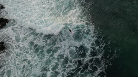 aerial tracking shot of surfer speeding on foamy waves of ocean during sunset time - tracking drone shot