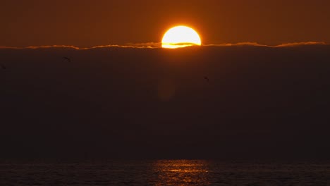 Salida-Del-Sol-Sobre-El-Horizonte-Del-Cielo-Nublado-Lapso-De-Tiempo-De-La-Bola-De-Sol-Cálido-Amarillo-Rojo-Sobre-La-Costa-Del-Mar-Del-Océano