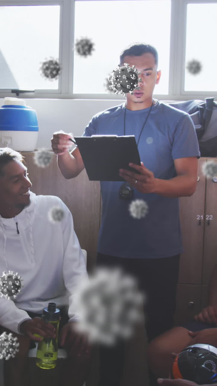 Animation of virus cells over diverse group of male football players with coach in changing room