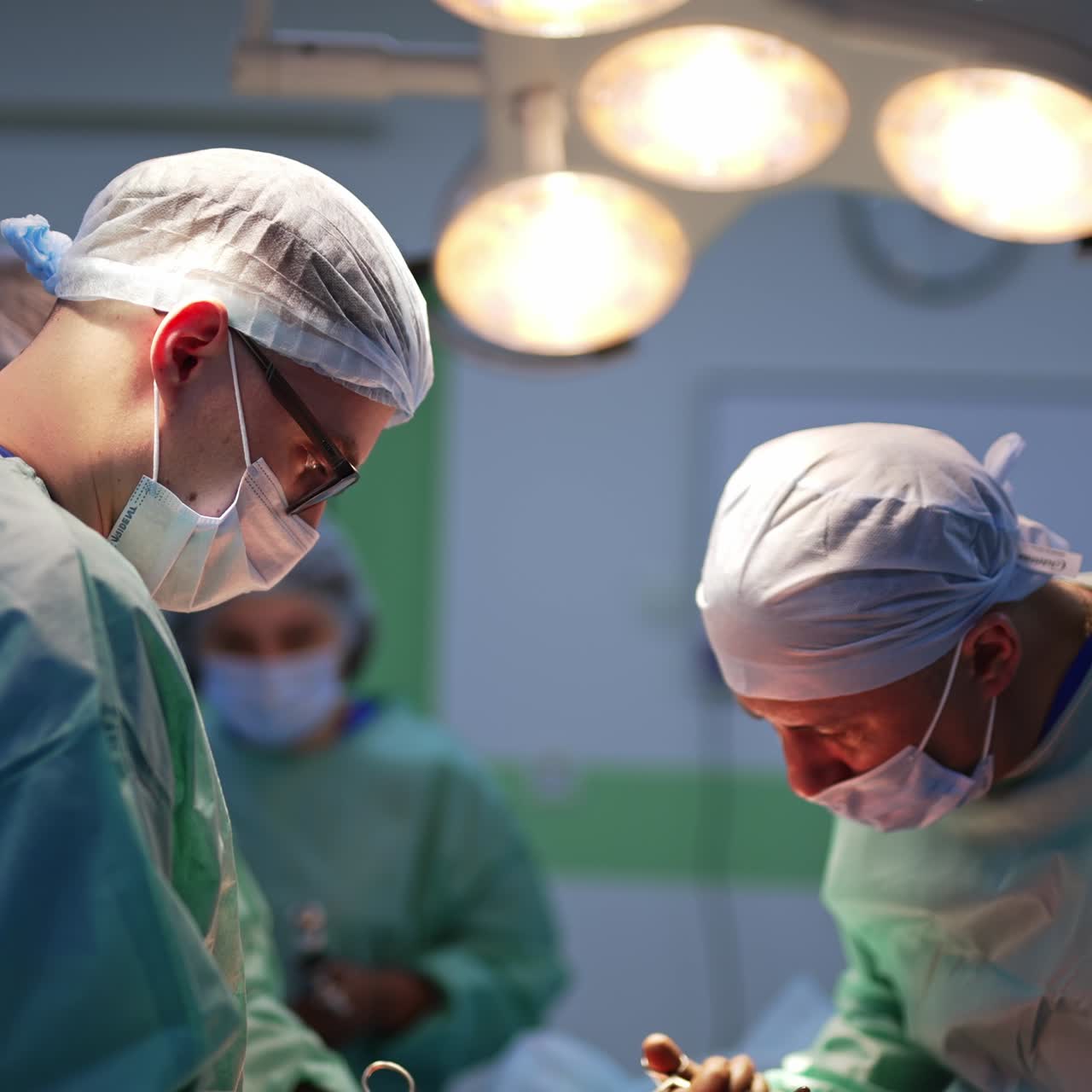 Et hold af mandlige kirurger, der arbejder på en operationsstue. Sundhedspersonale bruger metalværktøj til en plastikkirurgisk operation. Medicinsk personale i sløret baggrund