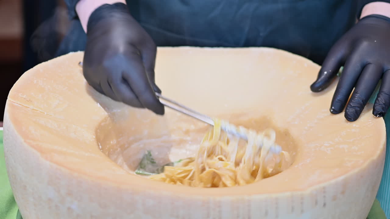 Man mixing the pasta from a heated parmesan wheel at a restaurant