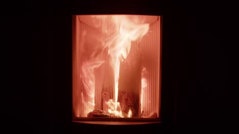 leña ardiendo con llama naranja en una pequeña y acogedora chimenea para calentar el hogar, fondo negro