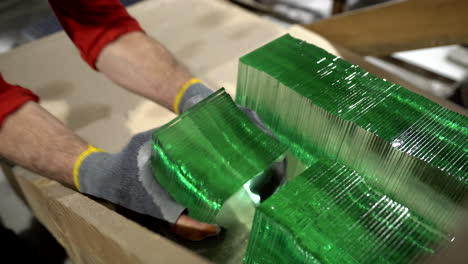 a worker taking green glass elements from a stack