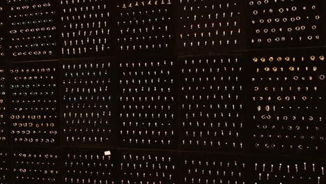 Display of body jewellery, including rings, studs, and barbells organized neatly on black panels. The collection features various sizes and styles, with metal and colored gem options