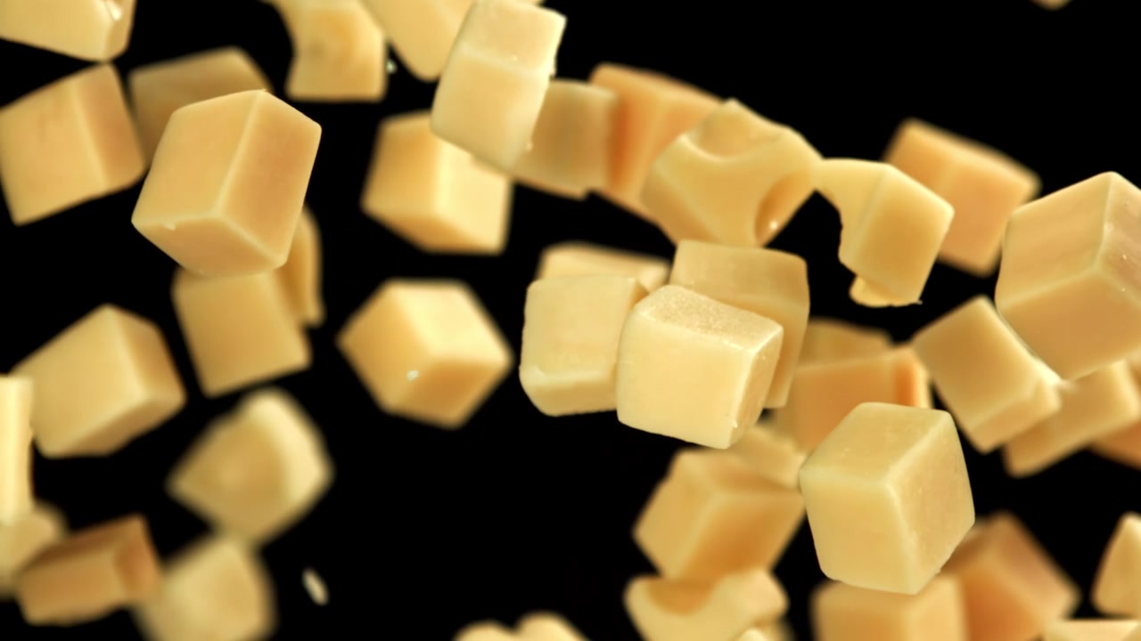 Ralenti de cubes de fromage tombant sur fond noir