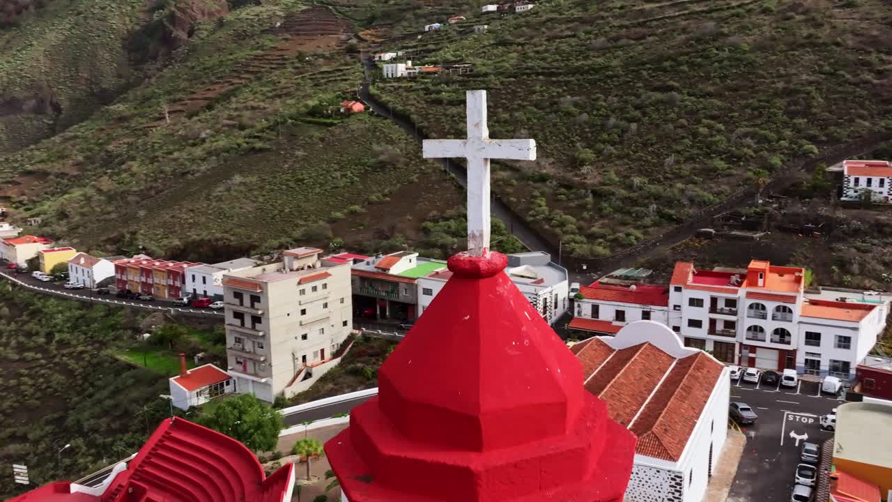 Red tower of Joapira church surrounded by valley slopes and Atlantic coast view