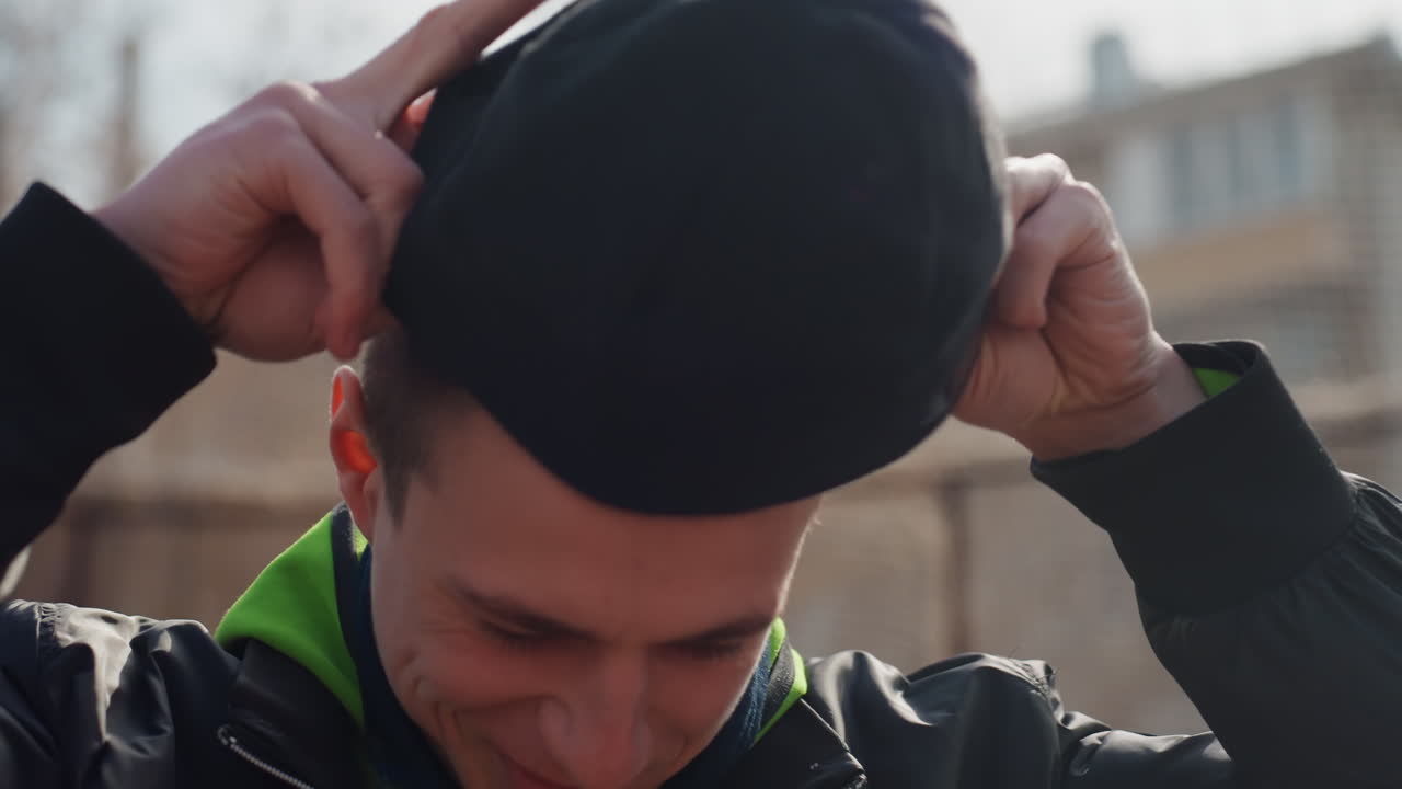 Un adolescente se prepara para un partido en una cancha de la ciudad; un jugador joven alista su equipo durante un tranquilo partido matutino; un adolescente se concentra en su rutina previa al partido bajo la suave luz del sol matinal en una cancha de baloncesto urbana.