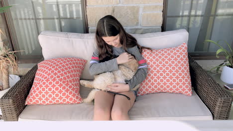 a cute little girl cradles and pets a sleeping golden doodle in her lap