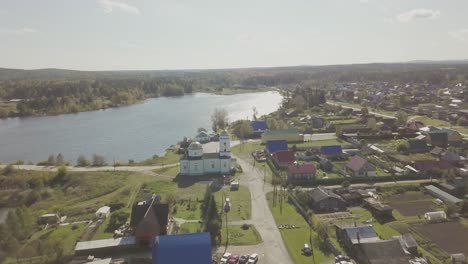 vista aérea de una aldea rusa junto a un río con una iglesia