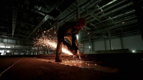 trabajador industrial está cortando barras de refuerzo metálicas con una sierra circular. construcción de una fábrica, hangar