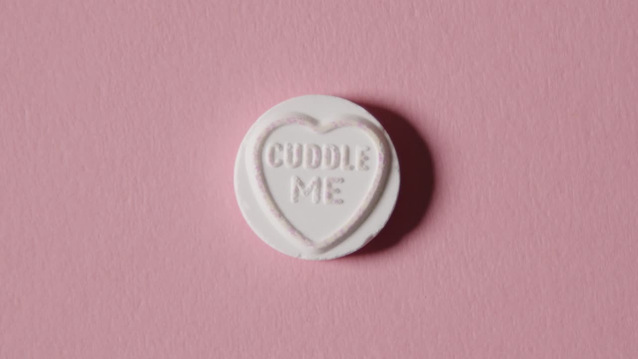 caramelo de corazón con un mensaje de abrazos sobre fondo rosa