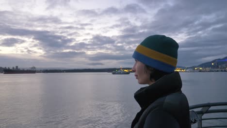 Mujer-Joven-En-La-Orilla-Del-Agua-Mirando-Fijamente-A-La-Bahía-Al-Atardecer-Cerrar-El-Perfil