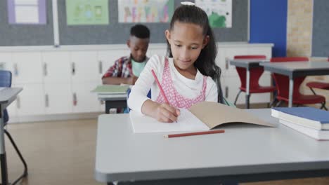 Fokussierte,-Vielfältige-Schulkinder,-Die-An-Schreibtischen-Im-Grundschulklassenzimmer-Schreiben,-Zeitlupe