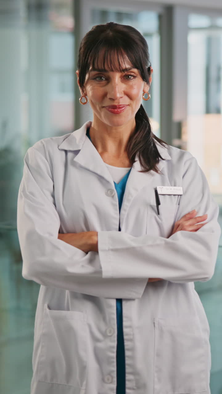 Doctora segura de sí misma sonriendo con los brazos cruzados en la clínica.