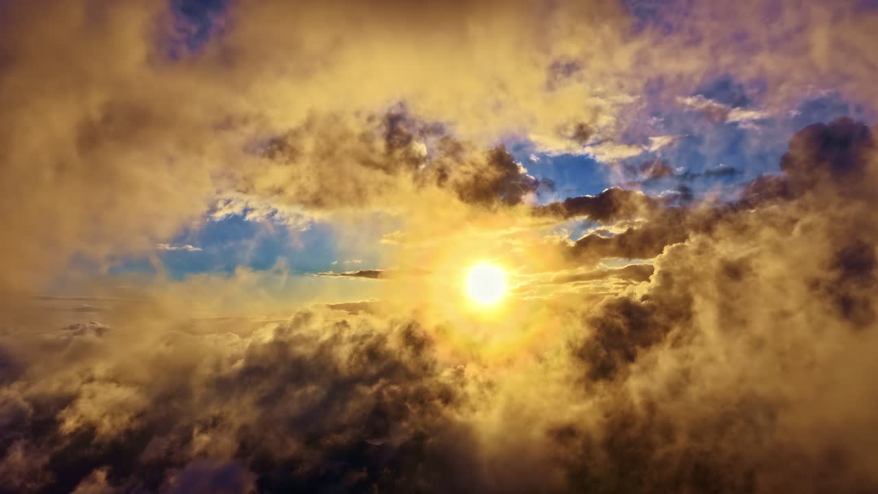 La luce dorata del sole squarcia le nuvole che si spostano mentre il drone vola all'indietro, rivelando un cielo spettacolare pieno di luce calda e una delicata profondità atmosferica
