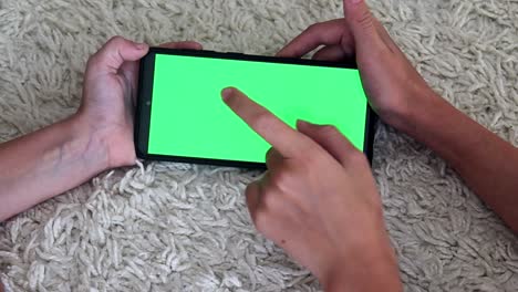primer plano de cuatro manos de niños presionan y ejecutan sus dedos en la pantalla verde del teléfono, deslizan lentamente hacia un lado, presionan el botón de navegación entrada de texto en línea lectura redes sociales juegos internet