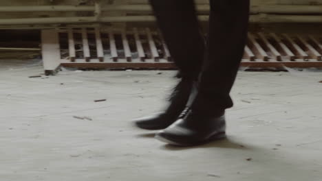 Adult-in-boots-walks-stealthily-inside-parking-garage,-crime-scene,-low-angle