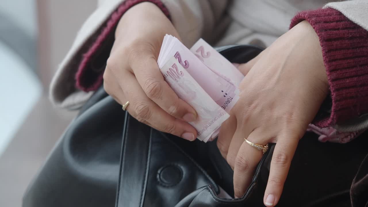Close Up of Woman's Hands Putting Turkish Lira Banknotes into Handbag