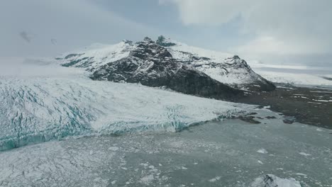 Icy-Glacial-Lake-by-Snow-Capped-Mountains-in-Wintry-Iceland-Landscape,-Aerial